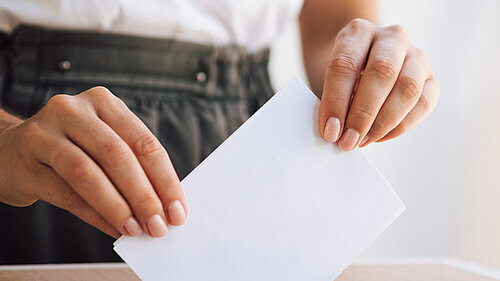 A person putting a ballot paper into a ballot box